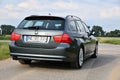 Back of BMW 330d (E91) touring green-gray station wagon on a country lane