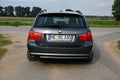 Back of BMW 330d (E91) touring green-gray station wagon on a country lane