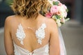 Back of the bride in a white wedding dress close-up. Bride`s bouquet of roses in pastel colors, curls. Angel wings in the decorati Royalty Free Stock Photo