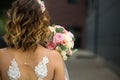Back of the bride in a white wedding dress close-up. Bride`s bouquet of roses in pastel colors, curls. Angel wings in the decorati Royalty Free Stock Photo
