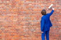 Businessman in blue suit standing at brick wall with paint roller