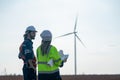 Back of Caucasian engineer man and woman discuss together with woman hold drawing paper and stay in front of row of windmill or Royalty Free Stock Photo