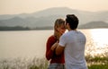 Back of Caucasian man kiss on forehead of beautiful woman with sunset light near lake and look romantic for couple love stay Royalty Free Stock Photo