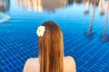 back of the caucasian woman with log hair and flower in it sitting on the edge of the swimming pool. Royalty Free Stock Photo