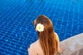 Back of the caucasian woman with log hair and flower in it sitting on the edge of the swimming pool. Royalty Free Stock Photo