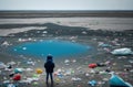 The back of a child standing and looking at a pile of garbage on the beach Conceptual view of a beach full of human waste.