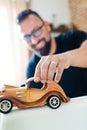 Back in childhood, man playing with wooden toy car