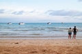 Back of a couple standing on the beach and looking to the sea with speed boats and bright sky in background at Koh Mak Island.