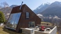 Back exterior of modern isolated villa with garden, surrounded by nature. Beautiful landscape of Swiss Alps