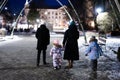 Back of family walk through the night city in the winter. Mother and three children in evening Royalty Free Stock Photo