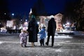 Back of family walk through the night city in the winter. Mother and three children in evening Royalty Free Stock Photo