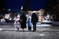 Back of family walk through the night city in the winter. Mother and three children in evening Royalty Free Stock Photo