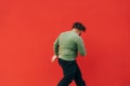 Back of a fat stylish guy dancing hip hop on a red wall background. An overweight man dances hip hop. Isolated Royalty Free Stock Photo