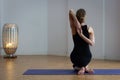 Back female yogi sitting in gomukhasana in studio