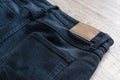 Back of jeans on wood background with leather label. Royalty Free Stock Photo