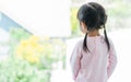 Back of little daughter girl wearing pink shirt or pyjamas, standing in living room or indoor bedroom at home, looking outside Royalty Free Stock Photo