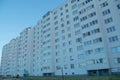 The back of a long nine-story apartment building with a white facade, with rows of Windows and loggias, going into perspective.