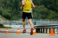 back male athlete running on asphalt with orange safety cones