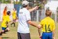 Back of male football coach wearing white COACH shirt at an outdoor sport field about to send in his young boy player in the game