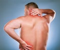 Back, man and pain with inflammation, injury and body ache with blue studio background. Mature male, gentleman or Royalty Free Stock Photo