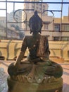 Back Metal show piece of Buddha sitting and meditating kept in window with black metal grill in background and buildings