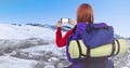 Back of millennial backpacker taking selfie against snowy hills Royalty Free Stock Photo