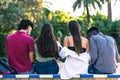 Back of a multracial group of students sitting on a bench outdoors studying Royalty Free Stock Photo