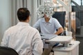 Back of optical staff prepare and use machine for processing of eyecare for children in optical shop Royalty Free Stock Photo