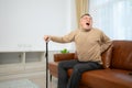 senior guy sits on a sofa with a walking stick in his living room at home Royalty Free Stock Photo