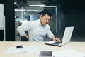 Back pain at the workplace. Young Asian businessman holding his back sitting in the office