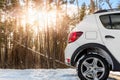 Back part of unknown small suv car parked at countryside dirt road in snowdrift near forest at snowfall on cold winter Royalty Free Stock Photo