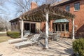The back patio of a brick home with seating under a pergola.