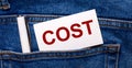 The back pocket of blue jeans contains a white pen and a white card with the text COST Royalty Free Stock Photo