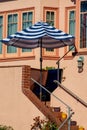 Back porch stoop or patio with stairs to entrance at residence with orange stucco facade exterior and visible umbrella Royalty Free Stock Photo