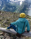 back portrait, a girl in a knitted hat sits on a bench and a blue jacket looks at the snow-capped mountains Royalty Free Stock Photo