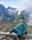 back portrait, a girl in a knitted hat sits on a bench and a blue jacket looks at the snow-capped mountains Royalty Free Stock Photo
