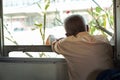 Back portrait of lonely old man sits in the train and looks out of window