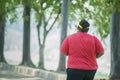 Back portrait view of unidentified fat man jogging