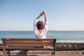 Back portrait woman sitting on a bench at the sea.amazing view,girl with curly hair,woman in white shirt,resting,spring holidays,s Royalty Free Stock Photo