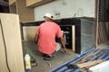 Back portrait of worker installs the oven into built-in furniture