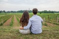 Back portrait a young couple in love sitting in the vineyard in spring looking at the horizon
