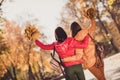 Back rear spine view photo of two people girls friends hug embrace enjoy october city park center walk hold maple leaves Royalty Free Stock Photo