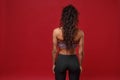 Back rear view of young african american sports fitness woman in sportswear posing working out  on red Royalty Free Stock Photo