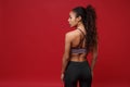 Back rear view of young african american sports fitness woman in sportswear posing working out  on red wall Royalty Free Stock Photo