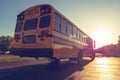 Back right low angle view of American Public school bus driving away with sunset in the distance Royalty Free Stock Photo