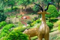 The back of sculpture of deer in a tropical park with flowers