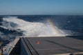 Back of a ship, wake and rainbow.