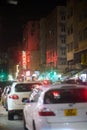 Back shot of cars in the street under neon light signs in Kowloon City at night. Vertical shot