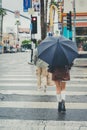 Back shot of a Fashionable young woman walks down a wet street with an umbrella