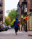 Back shot of female in a blue raincoat walking between building in a City of Boston During the Fall
